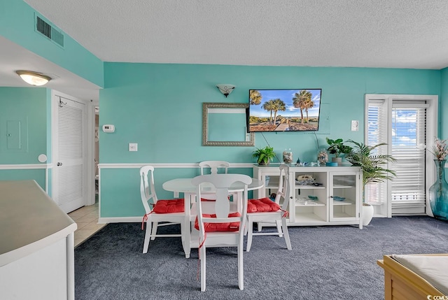 carpeted dining area featuring a textured ceiling