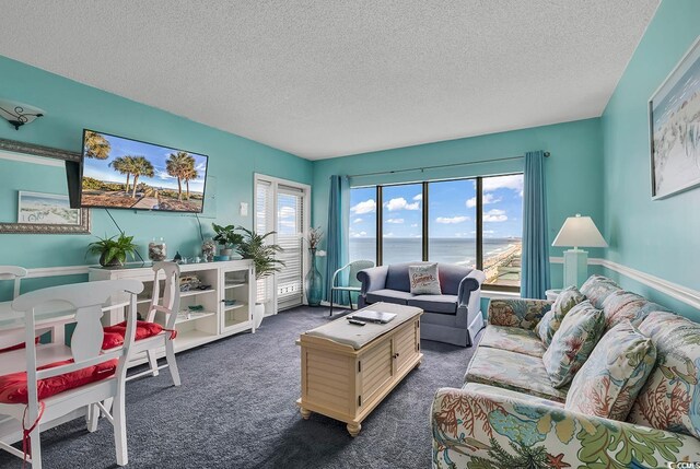 living room featuring a water view, dark carpet, and a textured ceiling