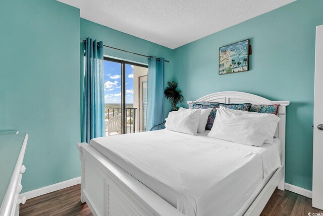 bedroom with access to exterior, a textured ceiling, and dark hardwood / wood-style flooring