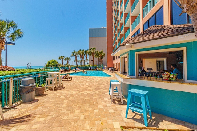 view of swimming pool with a water view, exterior bar, and a patio area