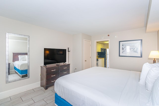 bedroom featuring connected bathroom and stainless steel fridge