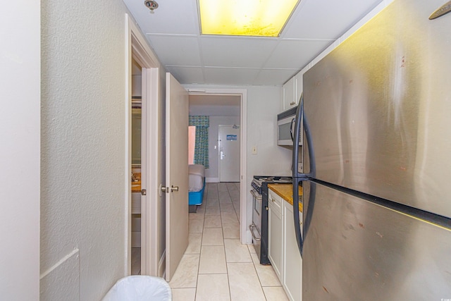 kitchen featuring white cabinetry, light tile patterned flooring, appliances with stainless steel finishes, and a drop ceiling