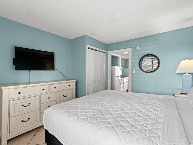 bedroom with white fridge, a closet, and light tile patterned flooring