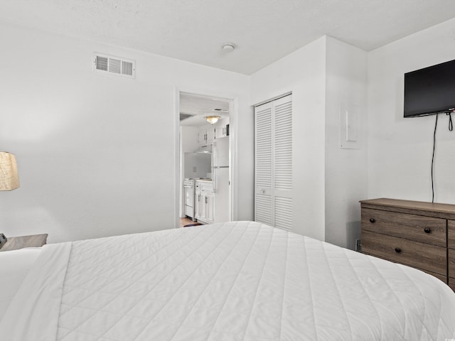 bedroom with ensuite bathroom, a textured ceiling, and a closet