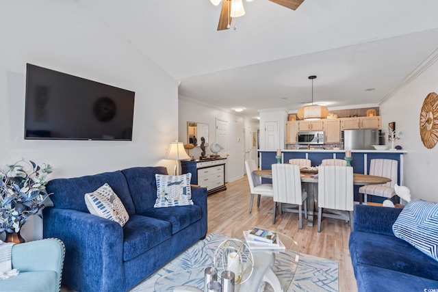 living room with ornamental molding, light wood-type flooring, ceiling fan, and vaulted ceiling