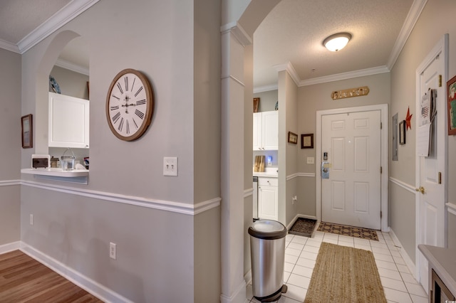 tiled foyer entrance featuring crown molding and a textured ceiling