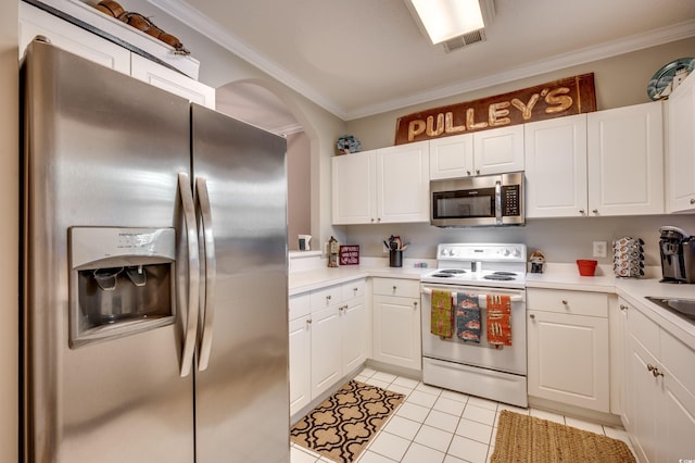 kitchen featuring crown molding, appliances with stainless steel finishes, light tile patterned flooring, and white cabinets