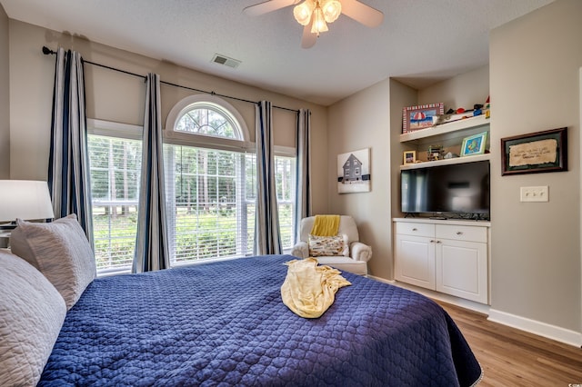 bedroom featuring ceiling fan, light hardwood / wood-style floors, and a textured ceiling