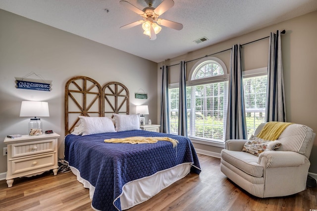 bedroom with ceiling fan, wood-type flooring, and a textured ceiling