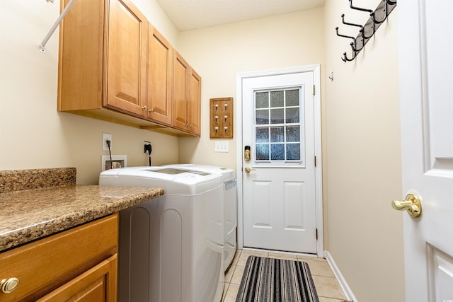 clothes washing area with cabinets, light tile patterned floors, washing machine and dryer, and a textured ceiling