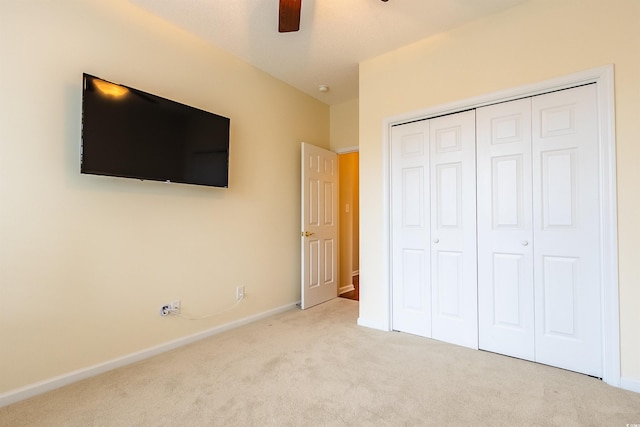 unfurnished bedroom with light colored carpet, a closet, and ceiling fan