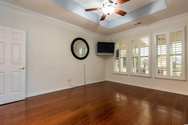 unfurnished room featuring ceiling fan, dark wood-type flooring, a raised ceiling, a textured ceiling, and ornamental molding