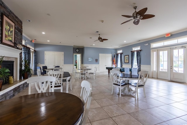 tiled dining room featuring a fireplace, french doors, ceiling fan, and ornamental molding