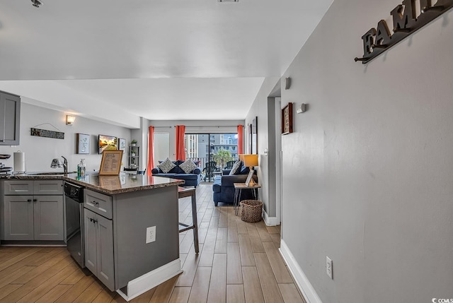 kitchen featuring stainless steel dishwasher, light hardwood / wood-style floors, gray cabinetry, sink, and kitchen peninsula