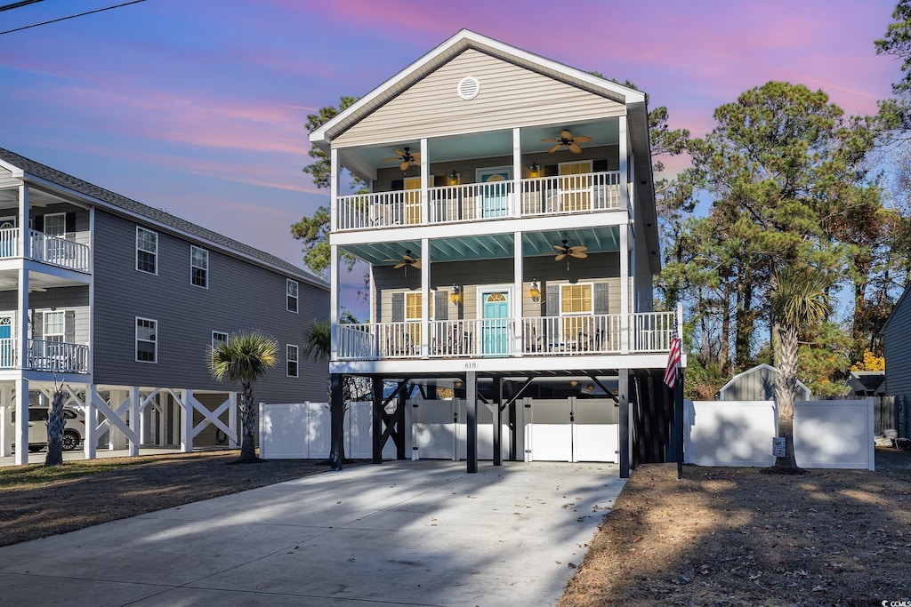 raised beach house with a balcony, a carport, ceiling fan, and a porch