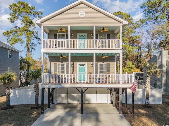 raised beach house featuring a carport, a balcony, covered porch, and ceiling fan