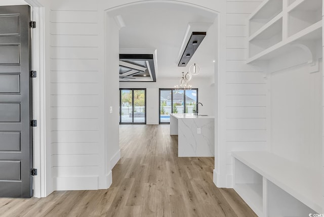 mudroom with a notable chandelier and light wood-type flooring