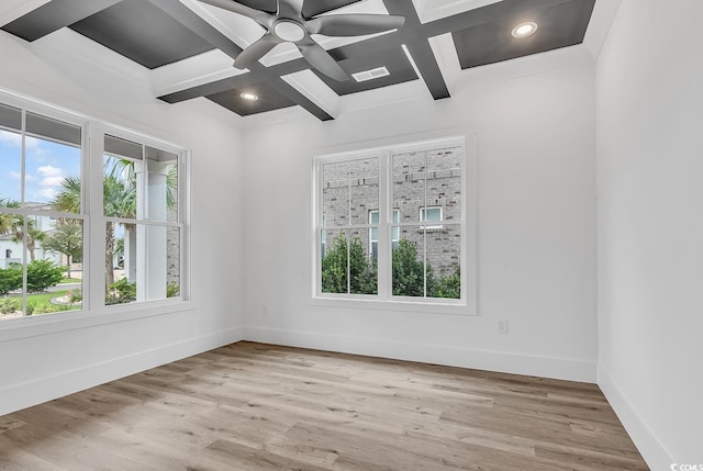 spare room with beamed ceiling, plenty of natural light, and light wood-type flooring