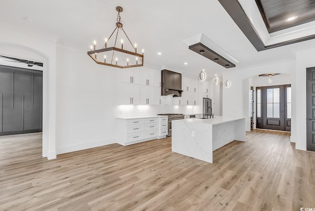 kitchen with light hardwood / wood-style flooring, white cabinets, hanging light fixtures, and high end stainless steel range oven