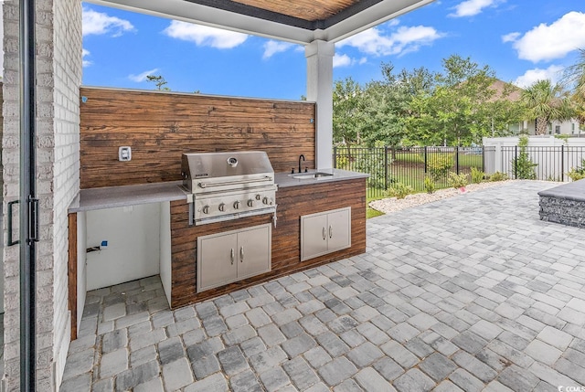 view of patio / terrace with area for grilling, a grill, fence, and a sink