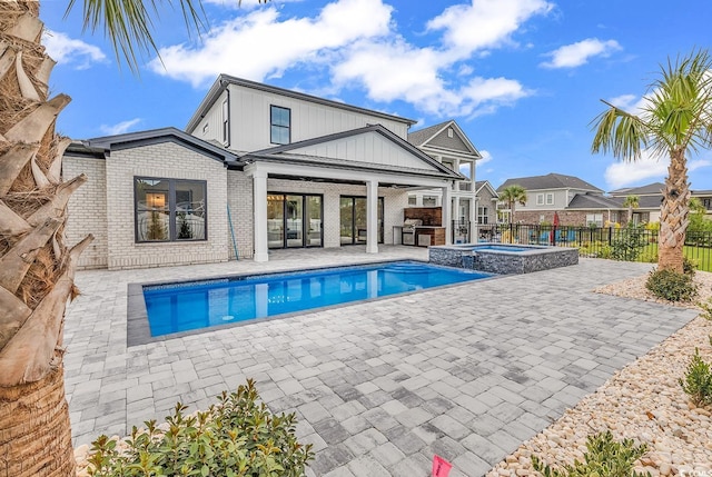 view of pool with a patio, fence, exterior kitchen, and a pool with connected hot tub
