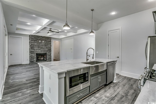 kitchen with dark hardwood / wood-style flooring, beamed ceiling, a fireplace, pendant lighting, and stainless steel appliances