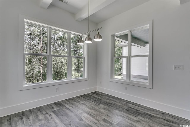 unfurnished dining area featuring beamed ceiling, a wealth of natural light, and dark hardwood / wood-style flooring