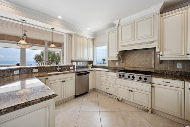 kitchen featuring stainless steel appliances, a water view, a sink, hanging light fixtures, and cream cabinetry