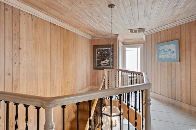 staircase with wooden ceiling, tile patterned flooring, wood walls, visible vents, and crown molding