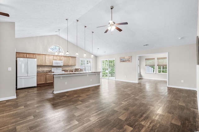 kitchen with dark hardwood / wood-style flooring, white appliances, an island with sink, and a breakfast bar area