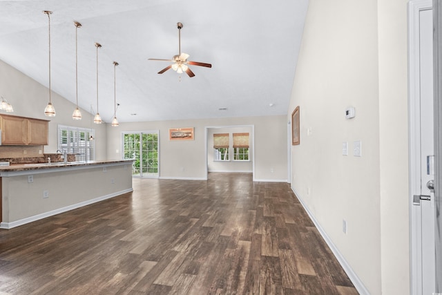 unfurnished living room with ceiling fan, sink, dark wood-type flooring, and high vaulted ceiling