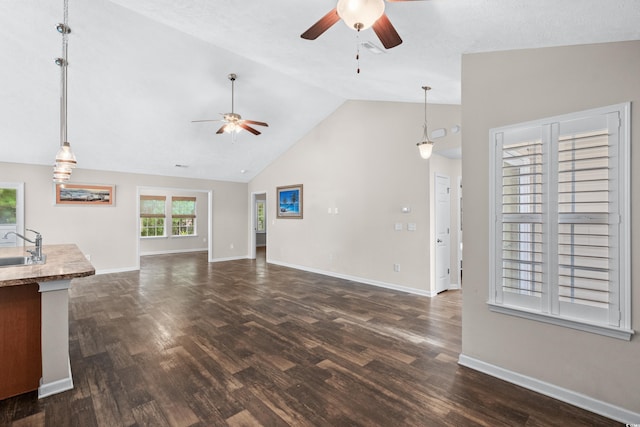 unfurnished living room with ceiling fan, dark hardwood / wood-style flooring, sink, and high vaulted ceiling