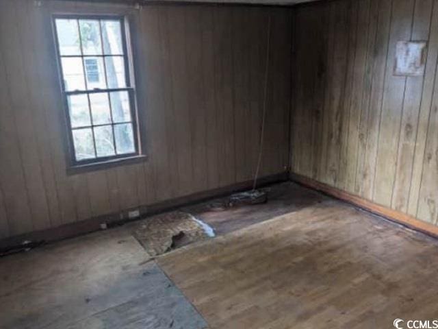 unfurnished room with wooden walls and wood-type flooring