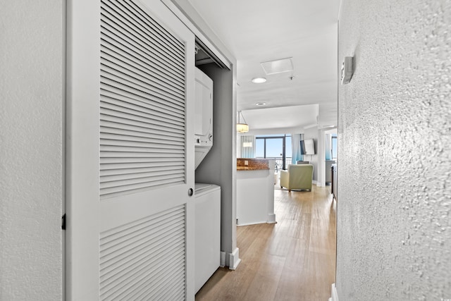 hall featuring stacked washer and dryer and light hardwood / wood-style floors