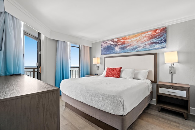 bedroom with a water view, hardwood / wood-style flooring, and ornamental molding