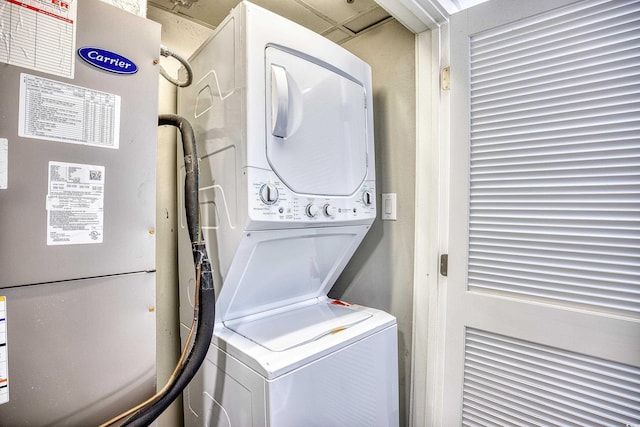 washroom featuring stacked washer / dryer and heating unit