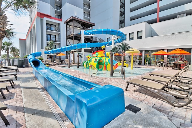 exterior space with pool water feature, a playground, and a water slide