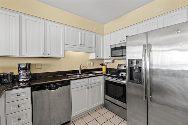 kitchen with appliances with stainless steel finishes, white cabinetry, sink, and light tile patterned flooring