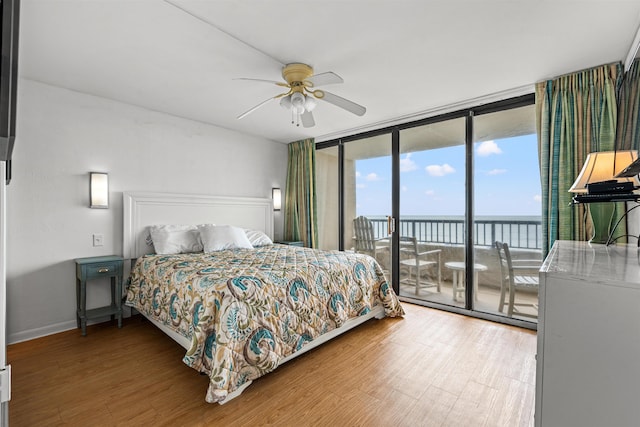 bedroom with wood-type flooring, ceiling fan, access to exterior, and floor to ceiling windows