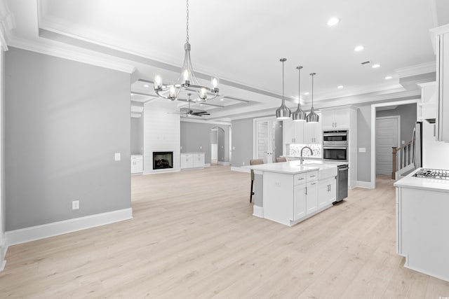 kitchen with light hardwood / wood-style flooring, white cabinetry, hanging light fixtures, and a center island with sink