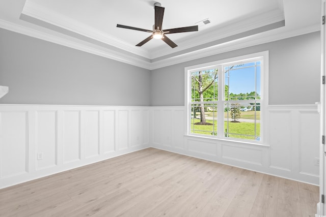 unfurnished room with light hardwood / wood-style floors, ornamental molding, a raised ceiling, and ceiling fan