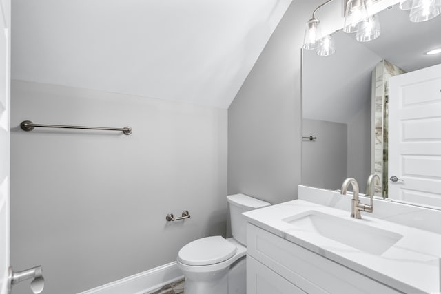 bathroom with toilet, vanity, and lofted ceiling