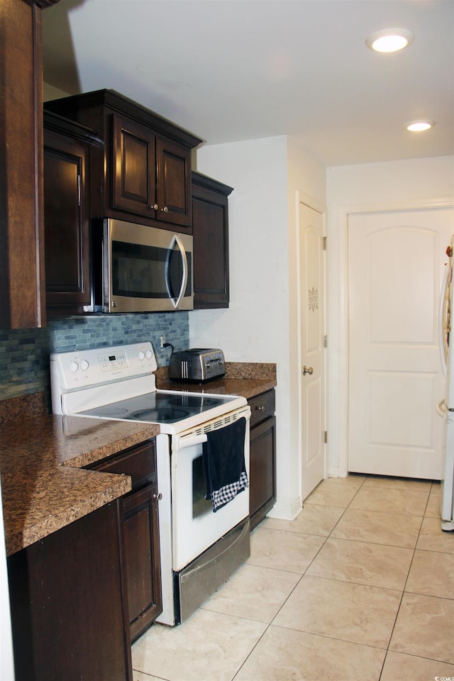 kitchen with light tile patterned flooring, white appliances, dark brown cabinets, and decorative backsplash