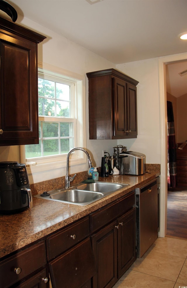 kitchen featuring light tile patterned flooring, dark brown cabinetry, dishwasher, and sink