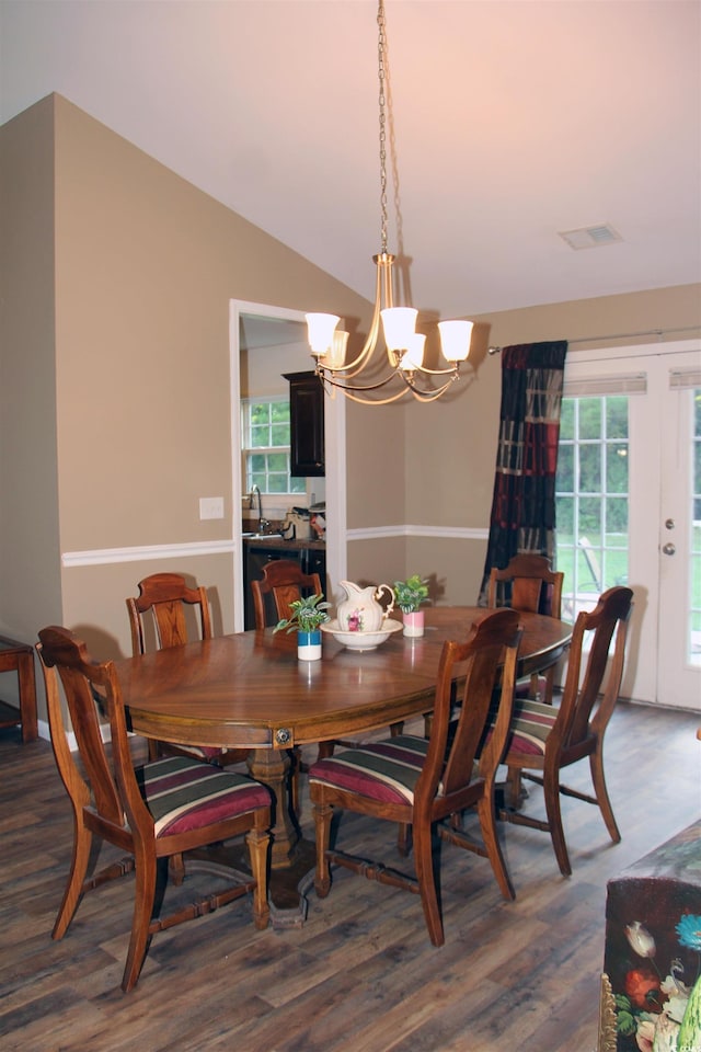 dining area featuring vaulted ceiling, dark hardwood / wood-style floors, sink, a chandelier, and french doors