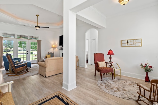 living room with light wood-type flooring, crown molding, french doors, ceiling fan, and a raised ceiling