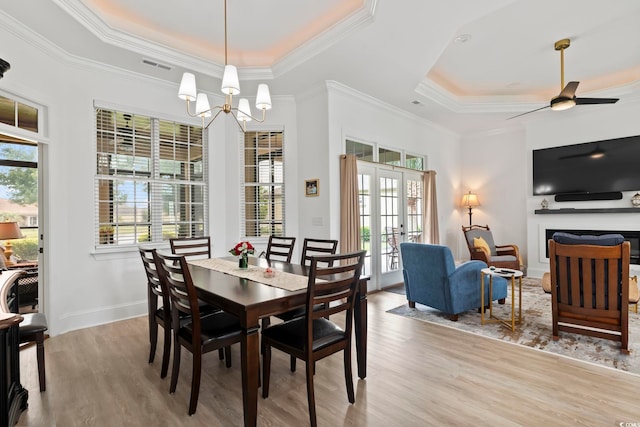 dining area with plenty of natural light, ceiling fan with notable chandelier, and a tray ceiling