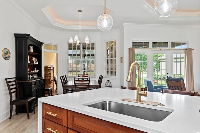 kitchen with light hardwood / wood-style flooring, sink, a raised ceiling, pendant lighting, and ornamental molding