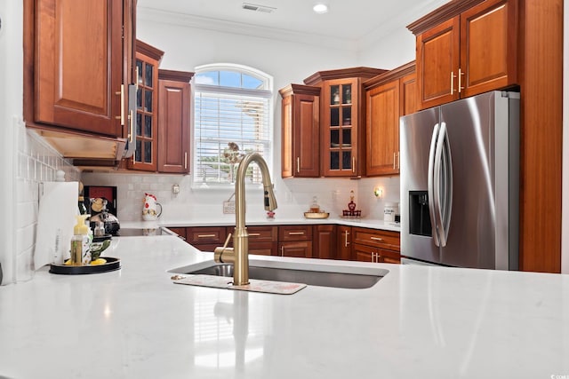 kitchen featuring ornamental molding, stainless steel fridge, sink, and decorative backsplash