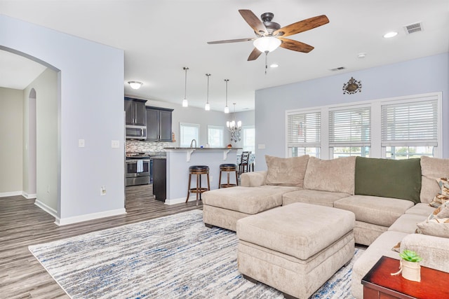 living room featuring sink, a healthy amount of sunlight, ceiling fan with notable chandelier, and wood-type flooring